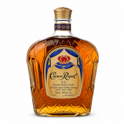 A bottle of Crown Royal De Luxe Canadian Whisky on a solid white background. The bottle is made of faceted crystal glass, filled with amber-colored whisky, and features a gold crown cap and a detailed cream, blue, and red label.